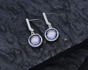 Detailed close-up of S925 silver drop earrings with round blue sapphire and pavé diamonds