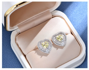 Macro detail of heart-shaped yellow gemstone earrings in a velvet display case