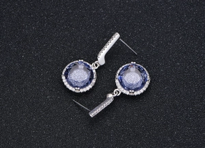 Macro detail of 11mm purple round-cut crystal drop earrings with halo setting on silver
