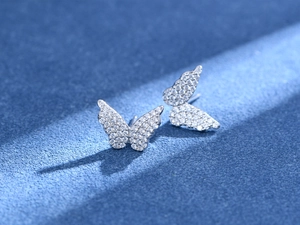 Macro di orecchini a farfalla in argento con zirconi scintillanti su sfondo blu
