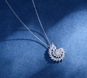 Macro shot of silver swirl pendant with marquise-cut stones on navy textured fabric
