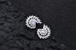 Gros plan de boucles d'oreilles tourbillon en argent serties de zircons sur pierre noire