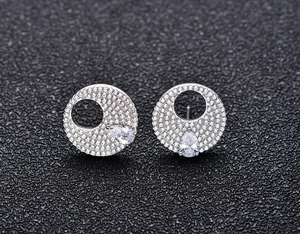 Macro shot of silver stud earrings with pave zircon and pear-cut yellow stones