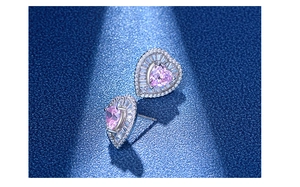 Macro view of heart-shaped pink zircon earrings with a sparkling white diamond halo