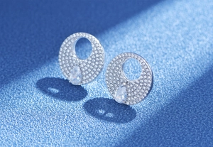 Macro view of S925 silver round paved earrings with a pear-shaped yellow zircon drop