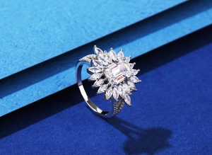 Macro shot of 925 silver ring featuring emerald cut center stone and marquise halo design
