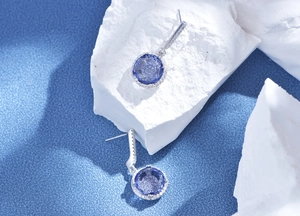 Macro shot of 11mm round purple gemstone earrings with halo diamonds on stone prop