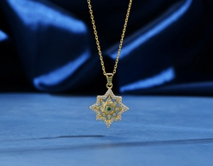 Dettaglio della collana a stella in oro 18k con diamanti bianchi e gemma verde smeraldo