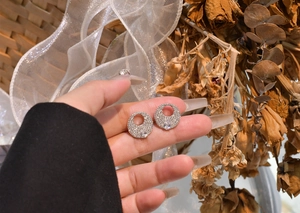 Detail of S925 sterling silver round earring with paved stones and pear-shaped center stone
