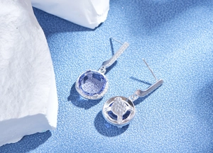 Detail of round purple zirconia earrings with S925 silver setting and honeycomb cutout