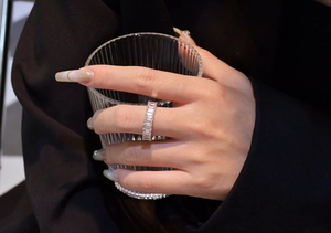 Detail of S925 sterling silver emerald cut full eternity ring on hand holding a glass