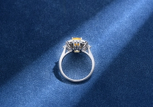 Détail d'une bague avec pierre jaune taille Asscher sur un fond en velours bleu foncé