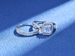 Bagues en argent avec coupe émeraude et pavé infini sur fond bleu en gros plan
