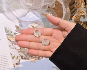 Detail of round S925 silver stud earrings with pave crystals and pear-cut yellow stones