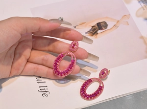 Detailed view of rose gold luxury earrings with pink tourmaline rhinestones on magazine