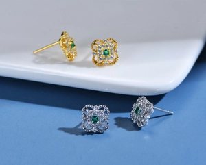 Detail of 925 silver four-leaf clover earrings with green gemstone and diamond accents