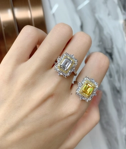 Gros plan de bagues taille émeraude jaunes et claires avec halo de diamants de luxe