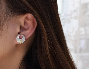 Macro shot of silver stud earring with yellow pear-cut gem and micro-set diamonds on ear