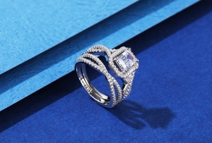 Détail macro d'une bague taille émeraude avec anneau croisé serti de trois rangées pavées