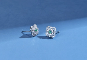 Macro view of clover silver earring with green gemstone and hollow vintage patterns