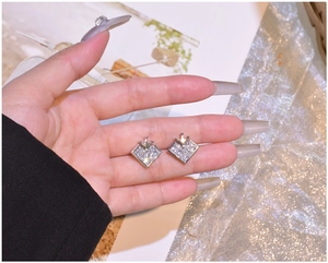Macro shot of silver 925 crown heart studs featuring diamond-cut square stones