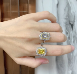 Détail d'une bague diamant jaune taille émeraude avec halo marquise sur le doigt