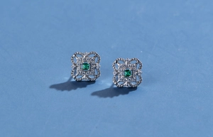 Detail of square lace-textured sterling silver earrings with green emerald and zircon gems