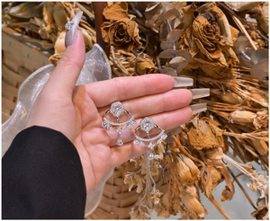 Detailed view of silver fan-shaped fringe earrings with pear-cut crystals and zircons