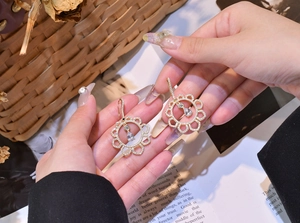 Close-up of gold flower earrings with pavé crystals and a pear-cut drop stone