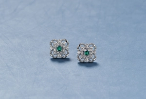 Macro detail of silver four-leaf clover stud with emerald gemstone and pavé diamonds
