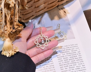 Detail of irregular hollow sunflower earrings with gold plating and paved micro diamonds