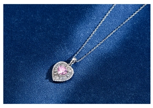 Macro shot of 925 silver heart necklace with pink stone on blue velvet backdrop