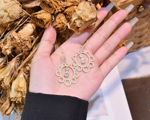 Detailed view of hollow sunflower earrings with sparkling zircons and pear-shaped drop