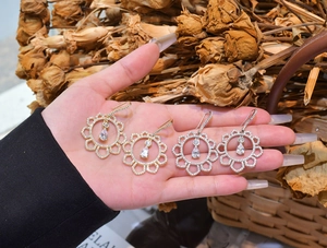 Detail of sunflower镂空 earrings with teardrop cubic zirconia in gold and silver finish