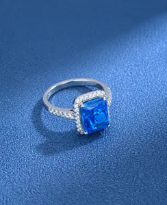 Close-up of radiant cut blue gemstone ring with micro-paved diamonds on platinum-plated silver