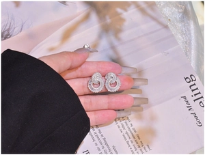 Close-up of silver double circle stud earrings with pave set zircon on a magazine page