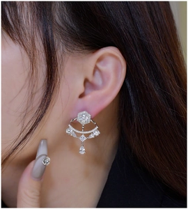 Close-up of fan-shaped silver earring with pear-cut zircon pendants on a model