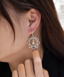 Detail of sun flower silver earrings with cubic zirconia drop stone on model