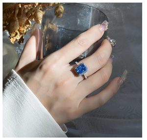 Macro detail of radiant cut blue gemstone ring with sparkling diamond halo in silver