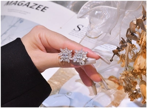 Vue détaillée des boucles d'oreilles flocon en argent avec cristaux tenues à la main