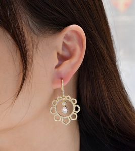 Detail of golden sunflower earrings featuring micro-pave diamonds and teardrop stone