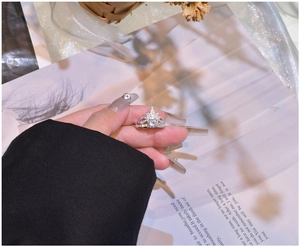Detailed view of silver crown clover ring with sparkling crystals on female hand