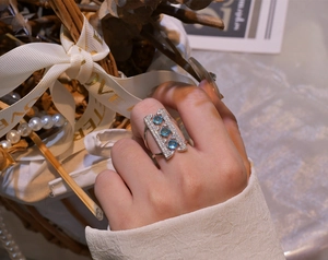 Detail of 925 sterling silver arch ring featuring blue gemstones and pave white diamonds