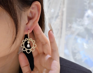 Macro detail of gold-plated hollow sun flower earrings with teardrop zircon drop