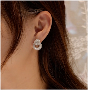 Macro view of interlocking silver double ring earrings with micro-pave crystals on earlobe