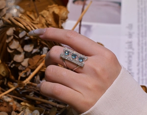 Close-up of sterling silver bridge ring with three blue stones and pavé set crystals