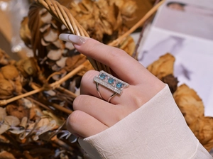 Macro detail of geometric silver ring featuring three sky blue gemstones and pave diamonds