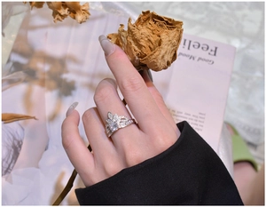 Close-up of a silver crown ring with white diamonds on a vintage magazine background
