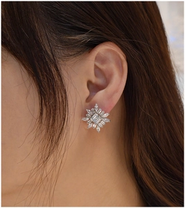 Gros plan d'une boucle d'oreille fleur en argent S925 avec zircons sur l'oreille du mannequin