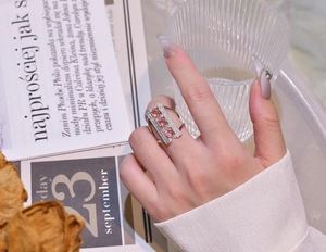 Detailed close-up of a silver arch bridge ring with pink crystals and small zircon stones